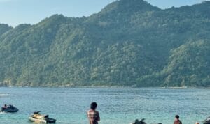 Pantai Lampuuk Aceh Besar dengan pasir putih, ombak laut, dan wisatawan menikmati aktivitas pantai